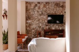a living room with a couch and a tv on a stone wall at Hostal Tunich Naj & Hotel in Valladolid
