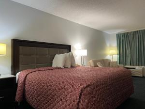 um quarto com uma cama grande e um edredão vermelho em Garden Inn & Suites em Metter