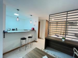 cocina con barra y 2 taburetes en una habitación en Flat moderno com piscina e academia, en Itaboraí