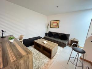 uma sala de estar com um sofá e uma mesa de centro em Flat moderno com piscina e academia em Itaboraí