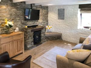 a living room with a stone wall with a fireplace at Cider Press Cottage in Fowey