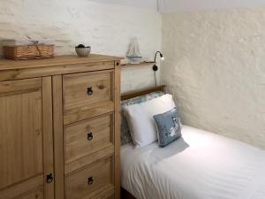 a bedroom with a bed with a dresser and a pillow at Cider Press Cottage in Fowey