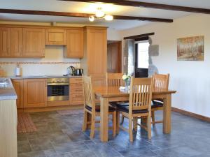 a wooden kitchen with a wooden table and chairs at Eglos Derry Farm Cottage - E4597 in Cury