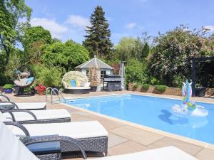 a pool with chairs and a grill in a yard at The Manor Coach House in Chilham