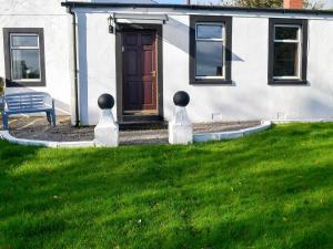 a house with a bench in front of a yard at Butterhole Cottage in Kelton