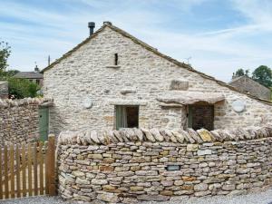 een oud stenen huis met een stenen muur bij Gelderslack Barn in Nateby