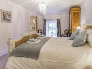 a bedroom with a large bed and a chandelier at Pwll Farmhouse in Llanllawdog