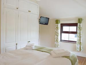 a bedroom with a bed and a tv on a wall at Brynhowell in Llanglydwen