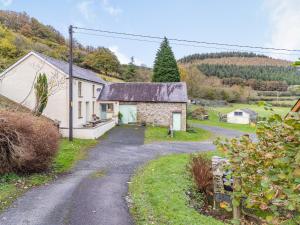 an old stone house with a gravel road at Pwll Farmhouse in Llanllawdog