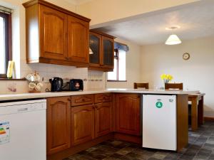 a kitchen with wooden cabinets and a white refrigerator at Bryn Villa in Newbridge on Wye