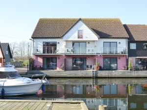 a boat is docked in front of a house at Kestrel Cottage in Horning