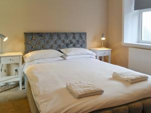 a bedroom with a large bed with two towels on it at Home Farm - Farmhouse in Dunragit