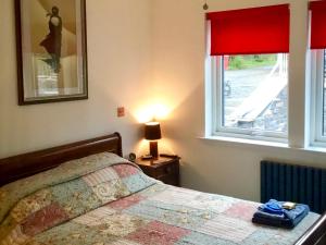 a bedroom with a bed and a window with red curtains at Tidereach - Otters View in Connel