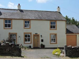 a white house with a brown door and a yard at Greenah View in Uldale