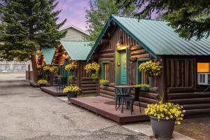 a log cabin with a green door and a table and chairs at The Bucking Moose in West Yellowstone
