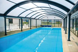an indoor swimming pool with a glass ceiling at Lagrange Vacances Domaine de Val Queven in Quéven