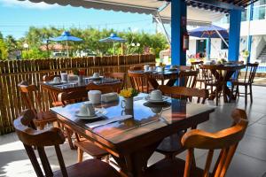 um restaurante com mesas, cadeiras e guarda-sóis azuis em Chalés Casuarinas em Japaratinga