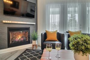 una sala de estar con chimenea y 2 copas de vino en LeChamplain #206 CITQ#248275 en Bromont