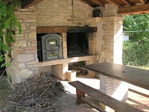 a stone oven with a wooden table and a bench at Appartamenti In Villa Elena in Grutti