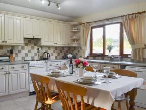 a kitchen with a table with a white table cloth on it at Higher Hopworthy Cottage-uk11436 in Pyworthy