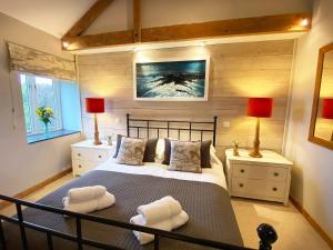 a bedroom with a large bed with two lamps and towels at Swallows Barn in Crowan