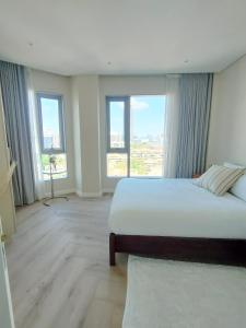a bedroom with a large bed and large windows at Spacious 2BR APT Near Sandton City -No Loadshedding in Johannesburg
