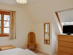 sypialnia z łóżkiem, telewizorem i krzesłem w obiekcie Westacre Lodge w mieście Fowlis Wester