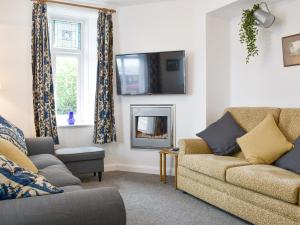 a living room with a couch and a tv on the wall at Underhill Cottage in Arnside