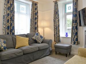 sala de estar con sofá y 2 ventanas en Underhill Cottage, en Arnside