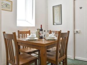 een houten tafel met stoelen en een fles wijn bij Underhill Cottage in Arnside