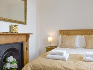 a bedroom with a bed with a fireplace and a mirror at Underhill Cottage in Arnside