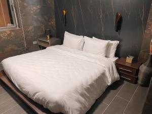a large bed with white sheets and pillows at Sky Suites East Legon in Accra