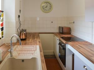 a kitchen with a sink and a clock on the wall at Porthysgaden in Twdweiliog