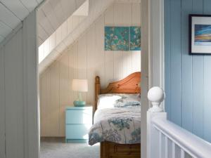 a bedroom with a bed with a blue wall at Shore Cottage in Arnisdale