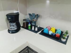 um balcão de cozinha com duas prateleiras com chávenas e comodidades para preparar café em Apartamento en centro de Popayán em Popayán
