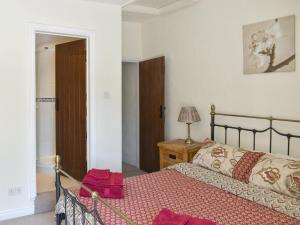 a bedroom with a bed and a table with a lamp at Poppy Cottage in Buckden