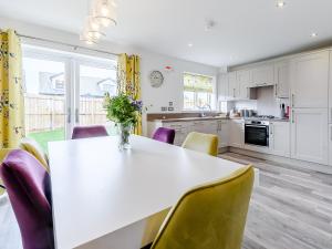 a kitchen with a white table and purple chairs at Coastal Retreat in Amble