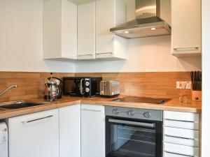 a kitchen with white cabinets and a stove top oven at Watersreach in Collieston