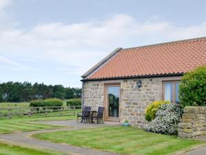 a stone house with two chairs and a patio at Bramble Cottage in Ripley