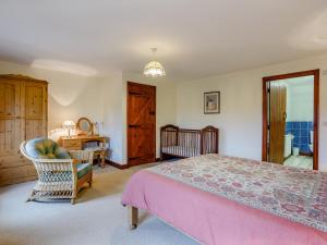 a bedroom with a bed and a chair and a crib at Purlin Barn - E3867 in Runcton Holme