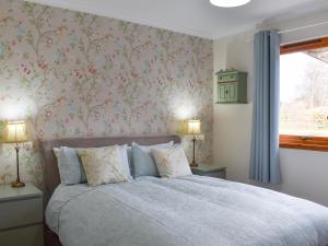 a bedroom with a bed with pink floral wallpaper at Cushendall House in Torcastle