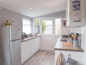 a kitchen with white cabinets and a white refrigerator at Ardlochan Cottage in Maidens