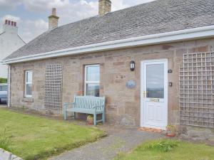 un banco azul sentado fuera de una casa de ladrillo en Ardlochan Cottage, en Maidens