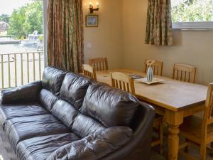 a living room with a leather couch and a wooden table at Watersedge - E1106 in Horning