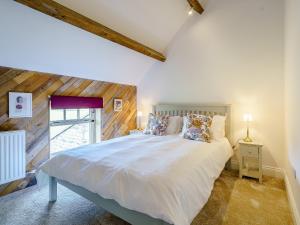 - une chambre avec un grand lit blanc et une fenêtre dans l'établissement Turnip Cottage, à Newsham