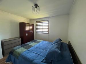 a bedroom with a blue bed and a window at Deptos Guacolda in Algarrobo