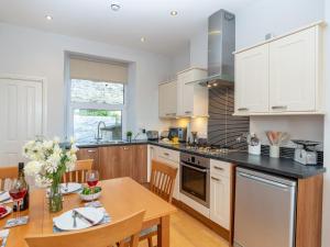 a kitchen with white cabinets and a wooden table at Apartment 2 The Wheelhouse in Fowey