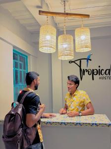 two men standing at a counter in a room at Tropical Hostel Santa Marta in Santa Marta