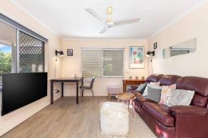 a living room with a leather couch and a flat screen tv at Relaxed Urangan Living at the Poolside Bungalow in Urangan