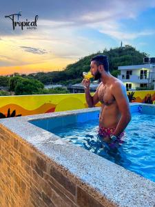 a man in a swimming pool drinking a drink at Tropical Hostel Santa Marta in Santa Marta